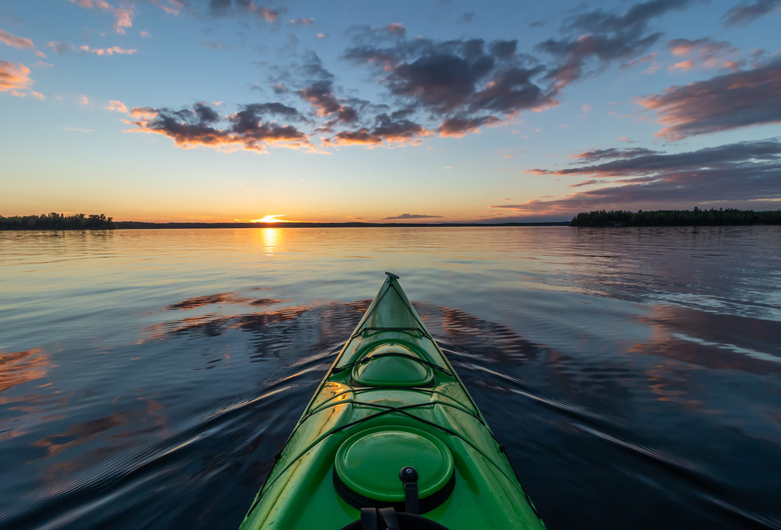 a sea kayak looking into the sunset on the ocean