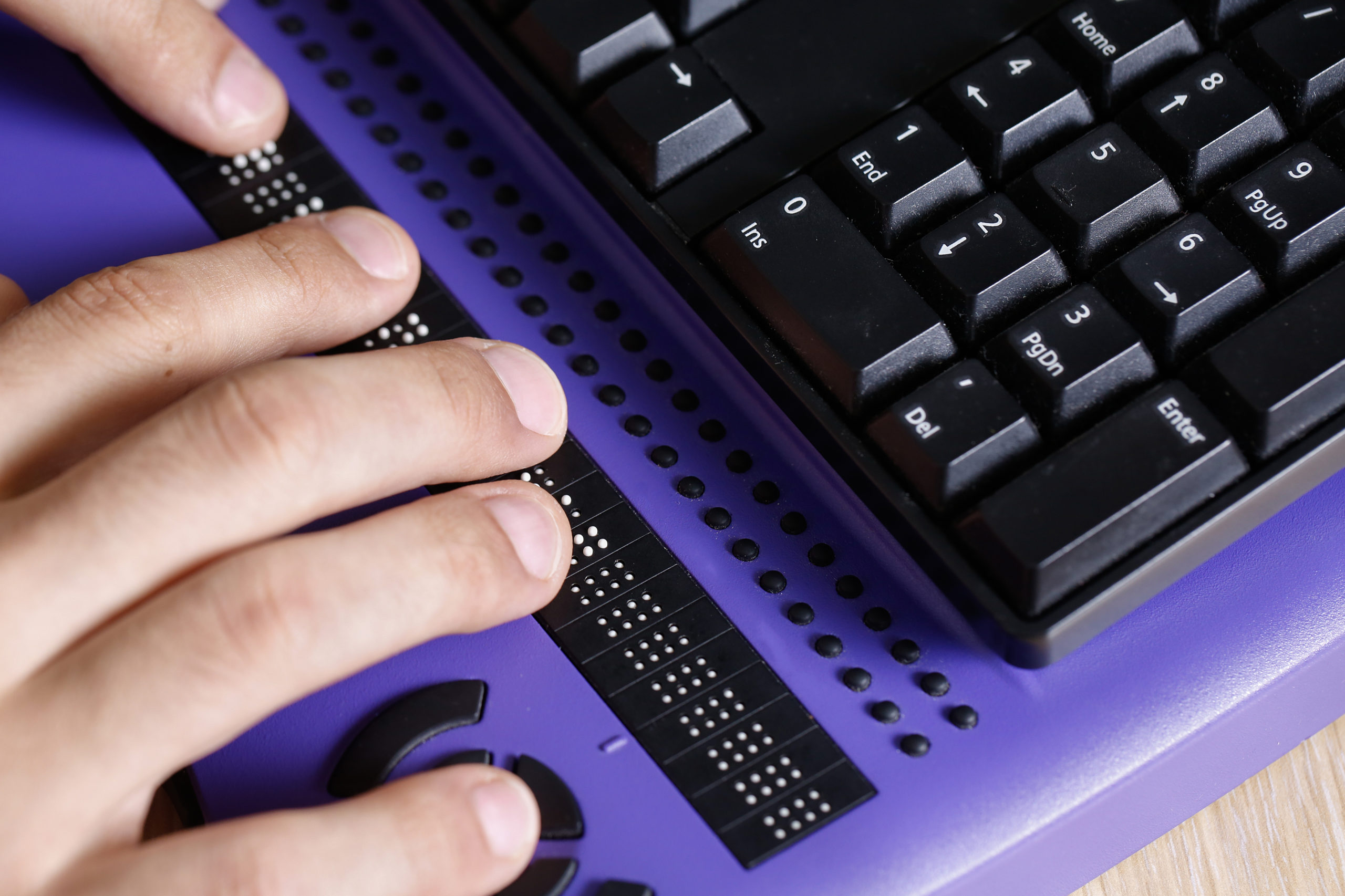 blind person using a computer with braille keyboard