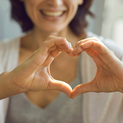 smiling woman making a heart shape with her hands