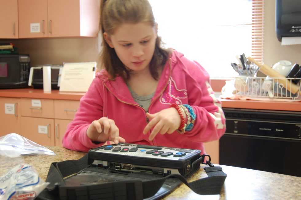 visually impaired girl using assistive technology in her kitchen