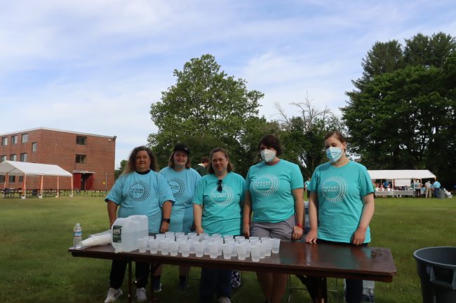 a group of five volunteers standing behind the water table