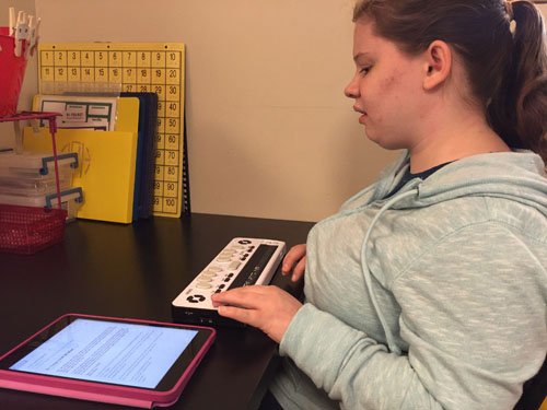 young visual impaired girl using assistive technology to use a tablet