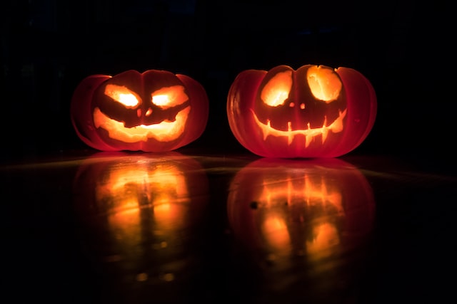 Two carved pumpkins lighting up in the dark