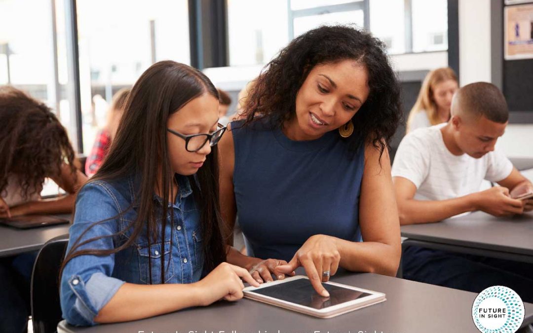 teacher showing a young girl student something on a tablet