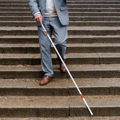 a blind man walks down the stairs with a cane