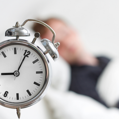 an alarm clock in the front with a person sleeping in the back