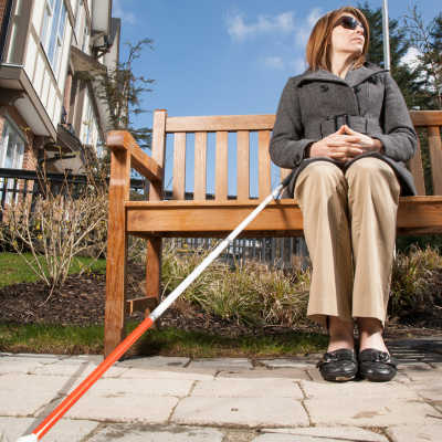 woman sitting on a bench with white cane