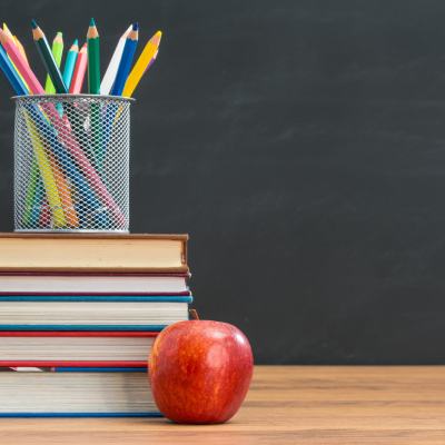 books, pencils, and an apple on a desk