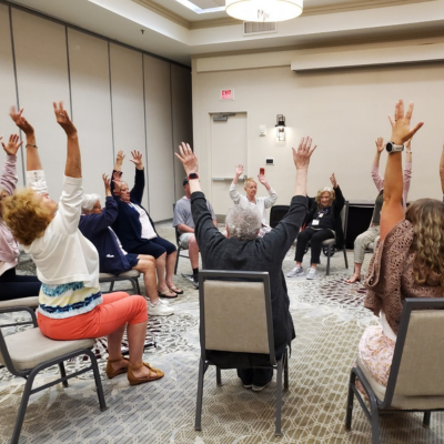 participants in a circle with their arms up doing some mobility exercises