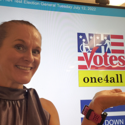 a staff member stands in front of a screen that says One 4 All voting