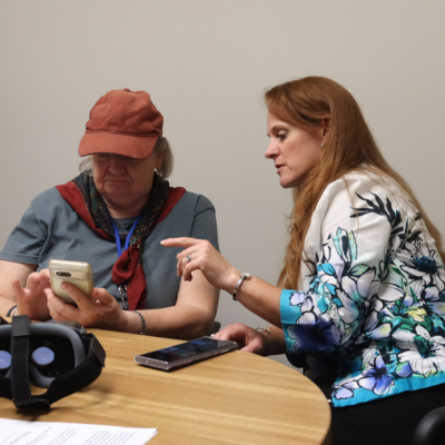 A woman assists a senior woman with her smart phone.