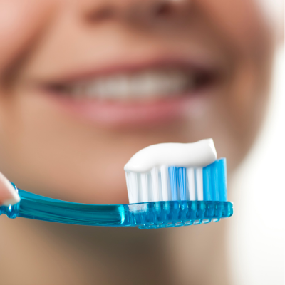 person holding out a toothbrush with toothpaste on it