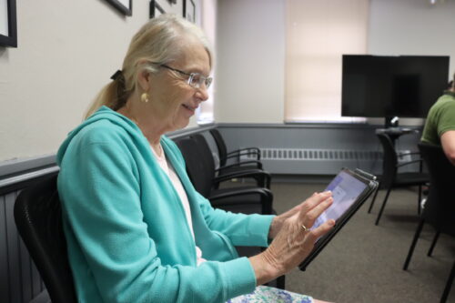 A senior woman confidently uses an iPad.