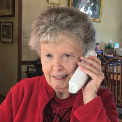 An older woman talks into a Clarity D 714 phone.