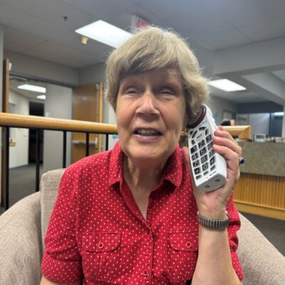 A senior woman uses a TEAP phone with the large buttons visible.