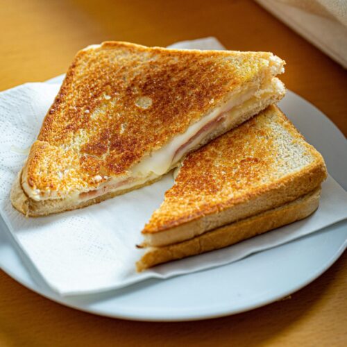 A golden brown grilled cheese sandwich cut into triangles.