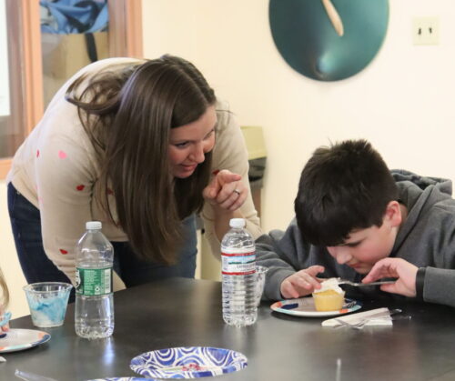 A Future In Sight staff member helps a young boy frost a cupcake at a previous Real World Skill-Building Session.