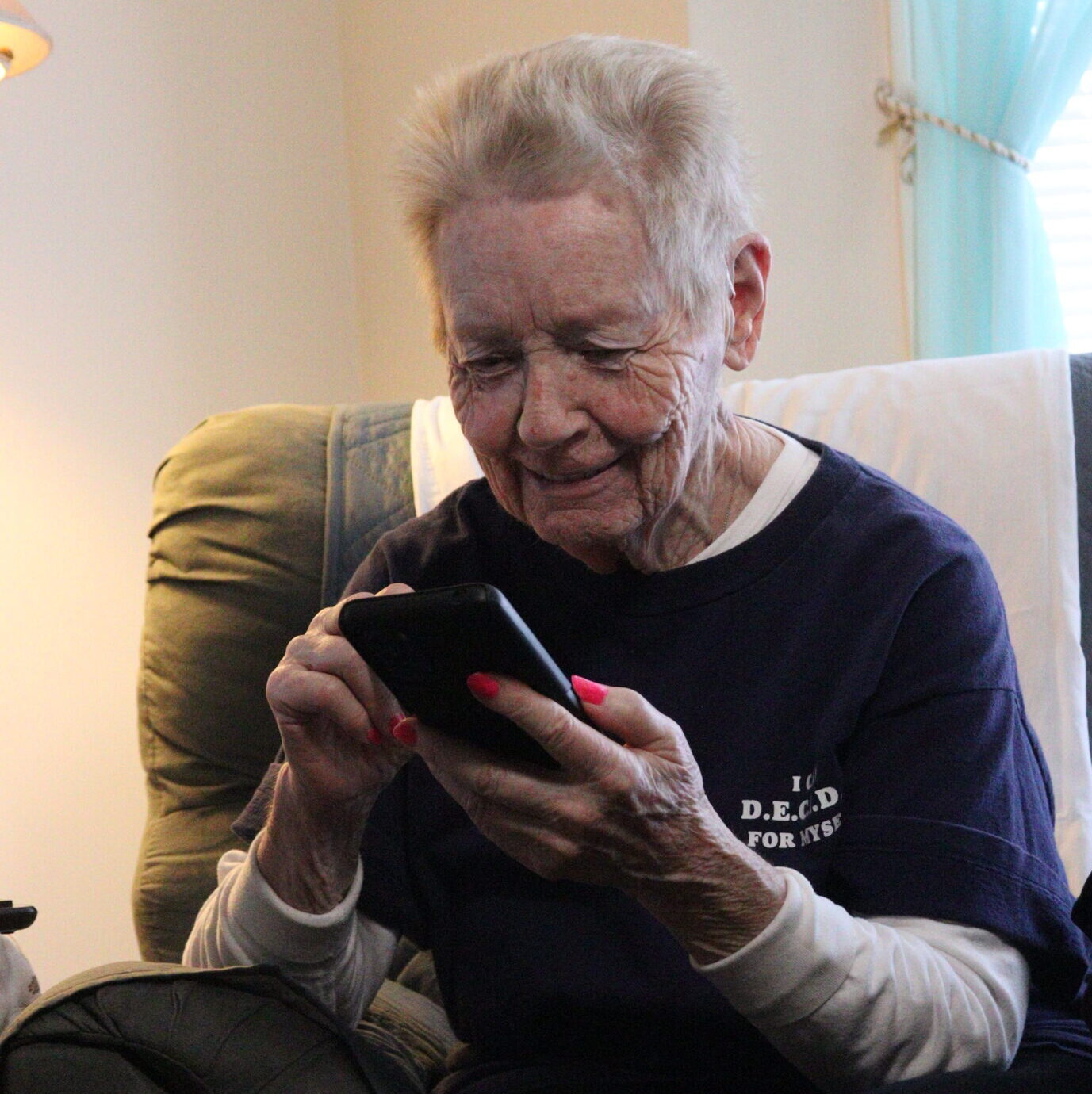 A senior woman uses her smartphone with a smile on her face.