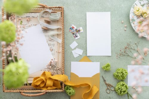 A variety of brightly colored papers, fabrics, flowers and ribbons on a table.