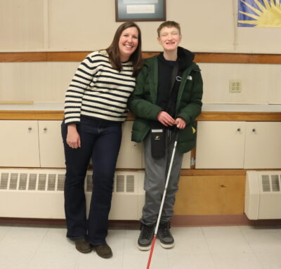 A female TVI with Future In Sight and a teen boy with a white cane posing together.