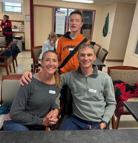 A teen boy poses with his parents.