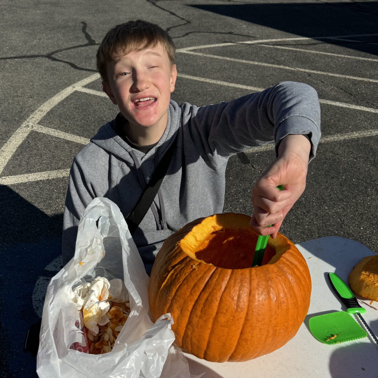 A teen boy carves a pumpkin.
