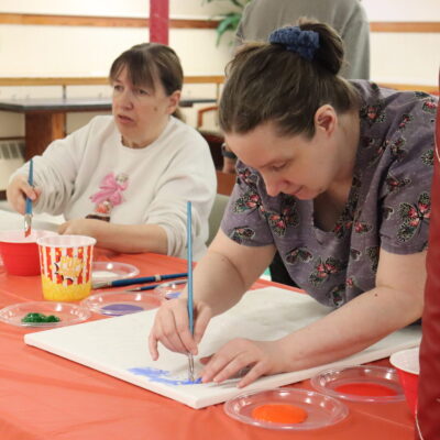 Two women painting canvases.