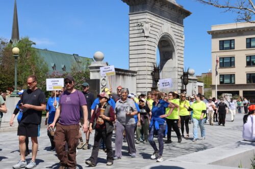 A group of walkers passing through the arch in front of the State House.