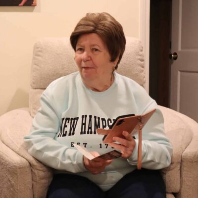 A senior woman uses her phone to read a card.