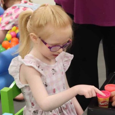 A child wearing glasses plays with clay.
