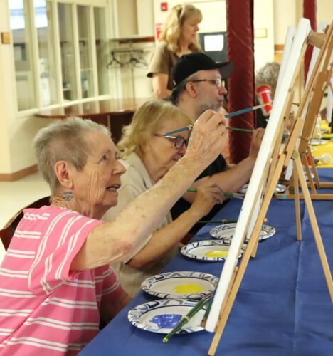 A group of individuals painting canvases.