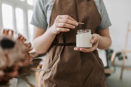 An individual in an apron holding a candle.